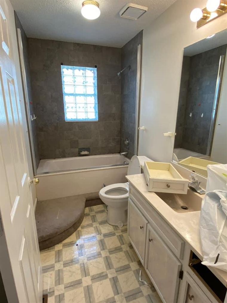 Dated bathroom with a corner tub, vinyl floor and old vanity