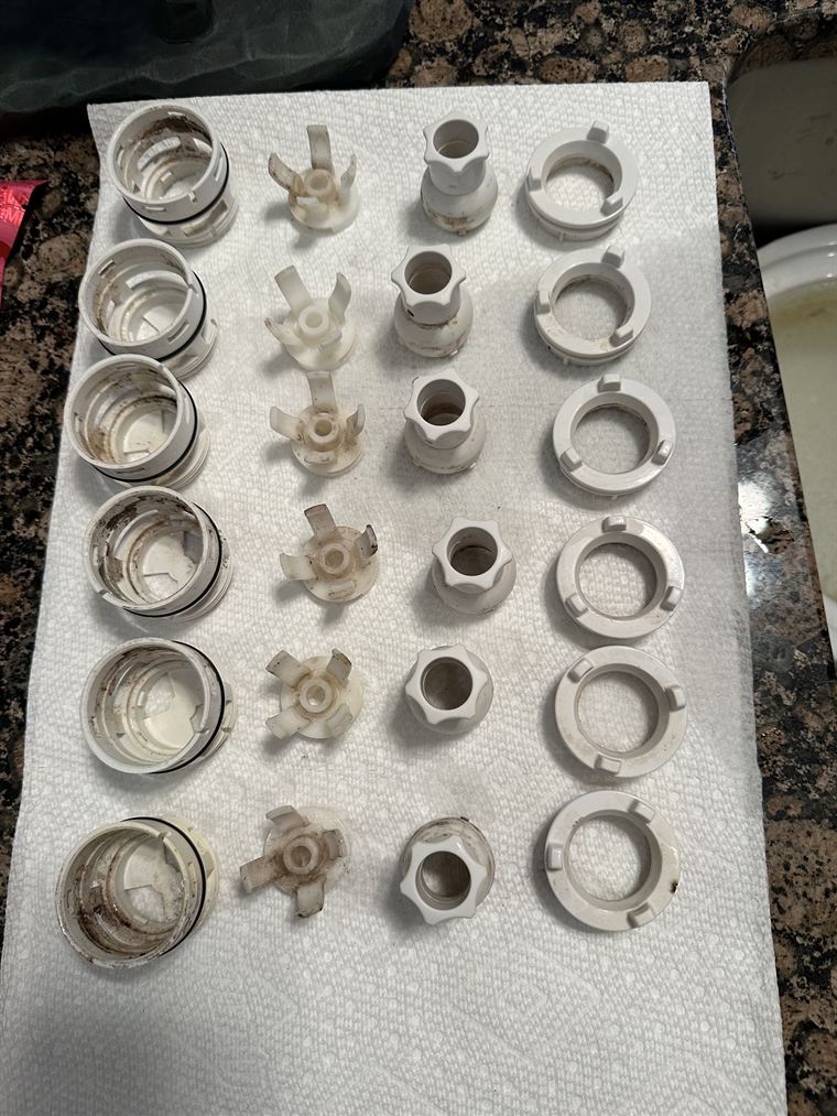 Jet housings and trim pulled from a whirlpool tub, showing scale and buildup