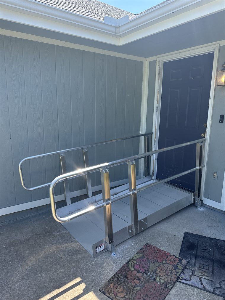 Aluminium wheelchair ramp with handrails at a residential entrance